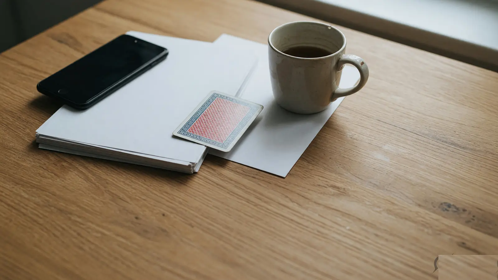 Reference desk with face-down phone, plain documents and a playing card